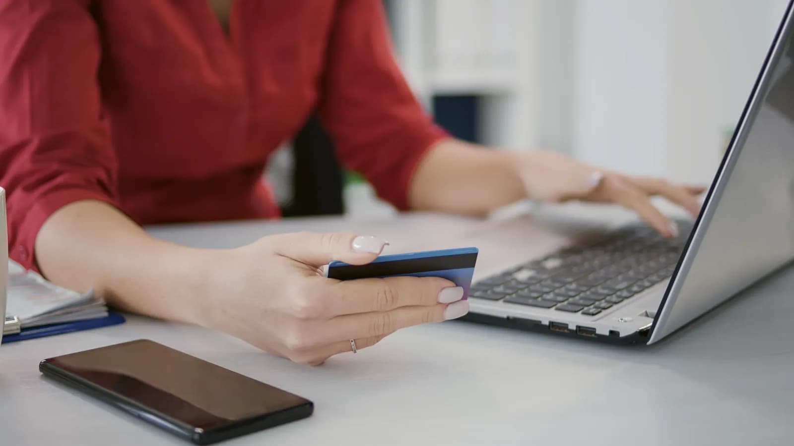 Une cliente tient sa carte bancaire devant son ordinateur portable, au moment de payer une commande en ligne